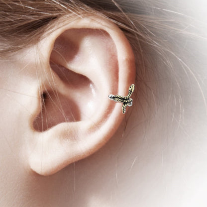 An antique gold snake helix earring cuff pictured on the ear of a model.