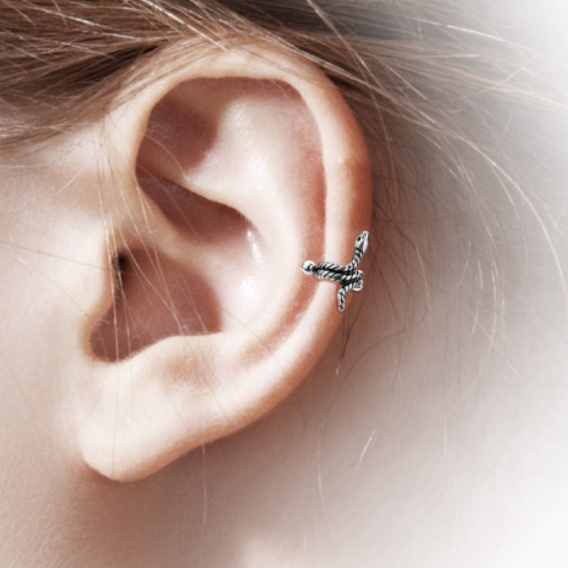 An antique silver snake helix earring cuff pictured on the ear of a model.