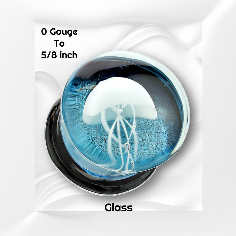 One of a pair of glass floating jellyfish gauges with a white jellyfish in front of a blue background with the ear gauge pictured on a white wavy background with black text stating the sizes available of this gauge earring.