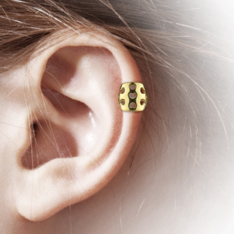 A gold plated heart helix earring with holes shaped like hearts pictured in the helix piercing of a model. 