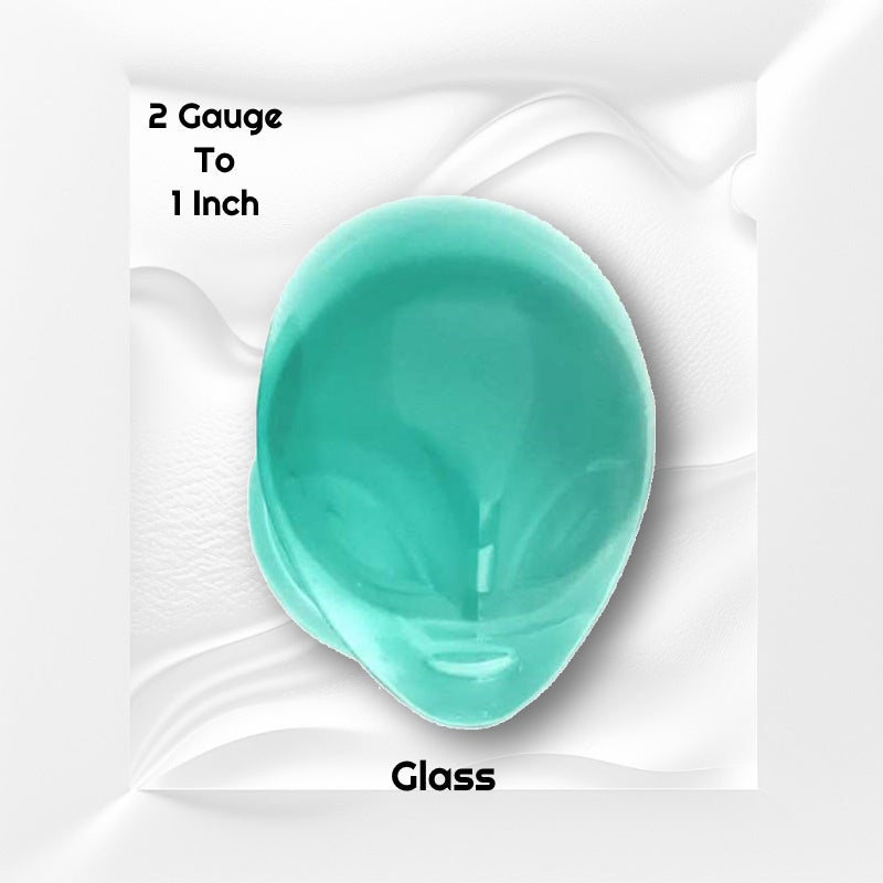 One gauge of a pair of pyrex glass alien plugs with a green face pictured on a white wavy background with black text stating the sizes available of this gauge earring.