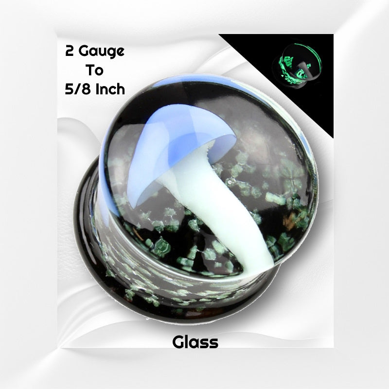 One of a pair of pyrex glass mushroom gauges with a blue top mushroom and a white stem all with a black background that has glow in the dark sparkles pictured on a white wavy background with black text stating the sizes available of this gauge earring.