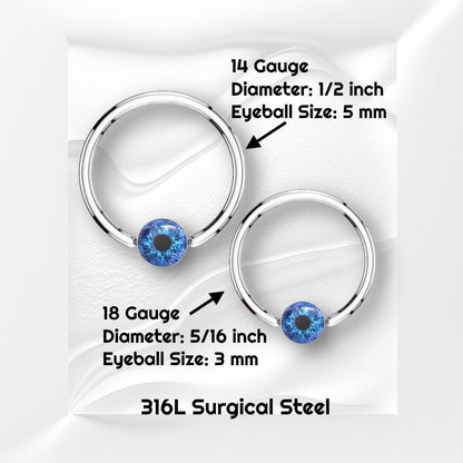 A surgical steel blue eyeball earring featuring a captive blue eyeball bead pictured against white wavy background with black text stating the size available of this horseshoe earring.