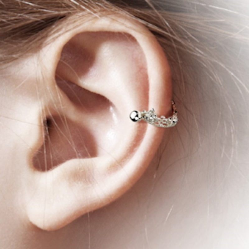 A surgical steel crown earring cuff pictured on the ear of a model.