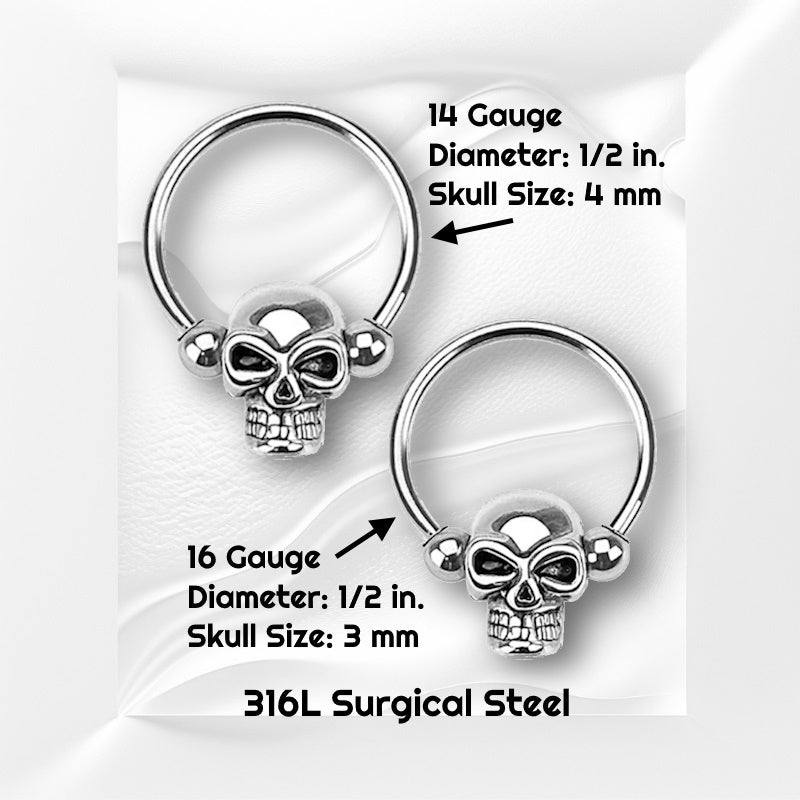 Two sizes of a surgical steel skull earring pictured against white wavy background with black text stating the size available of this captive bead circular earring.